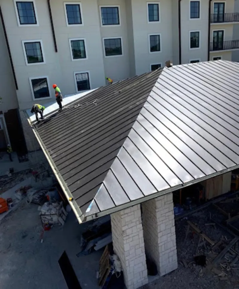 Crew installing standing seam metal roof panels on a commercial project in Oak Ridge
